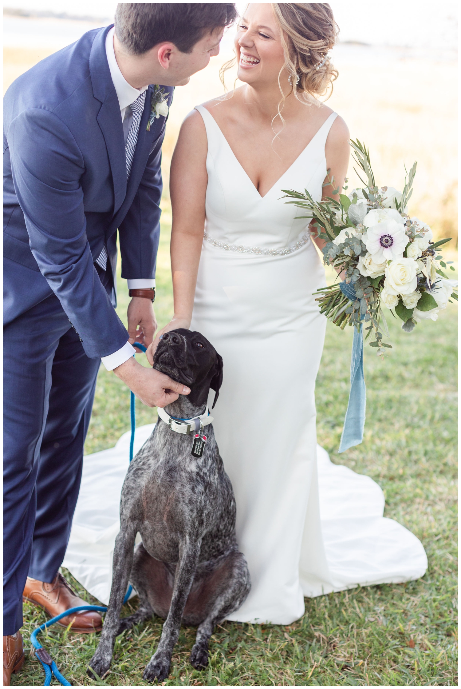 married couple posing with their dog on their wedding day