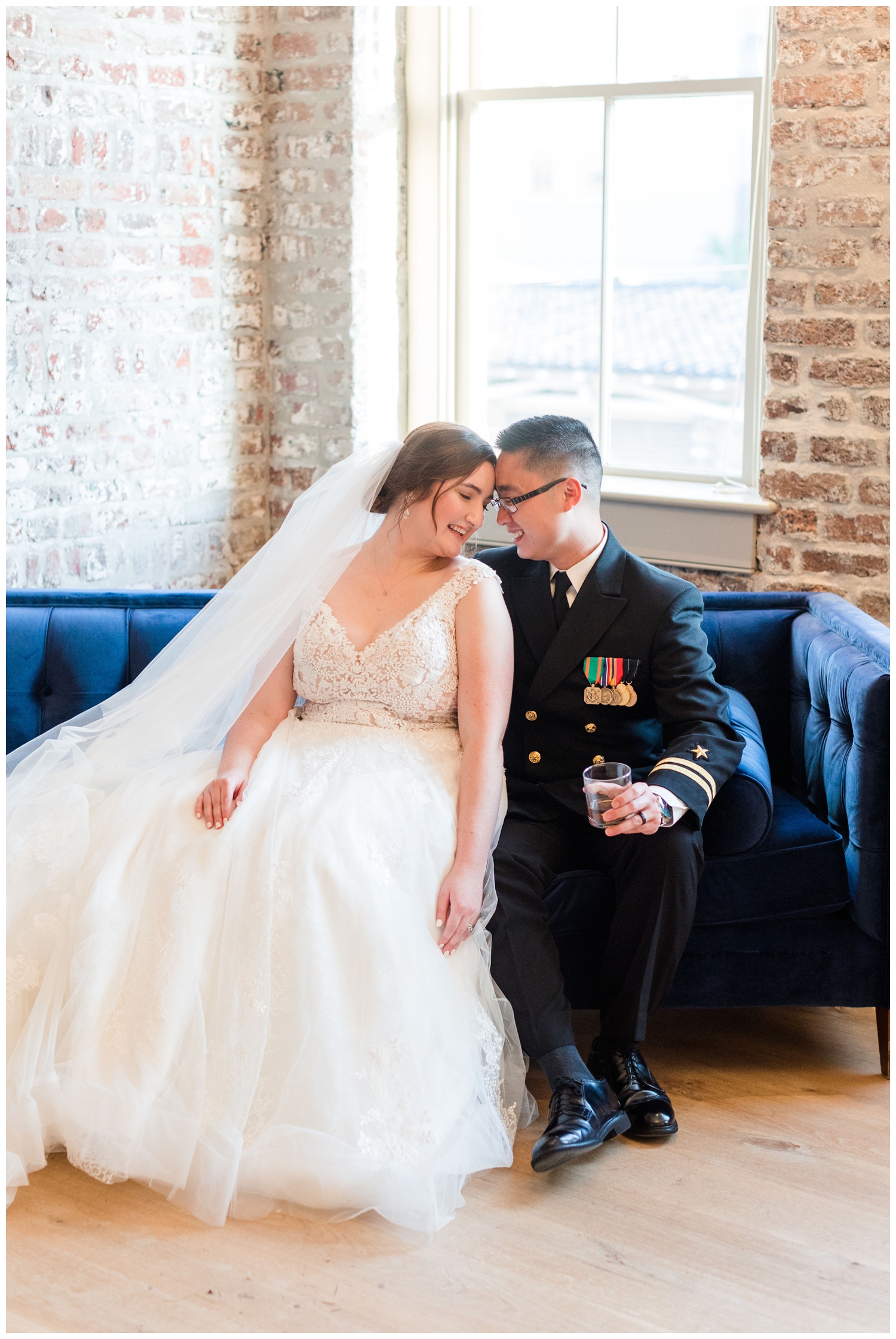 bride and groom sitting on blue couch inside Merchants Hall