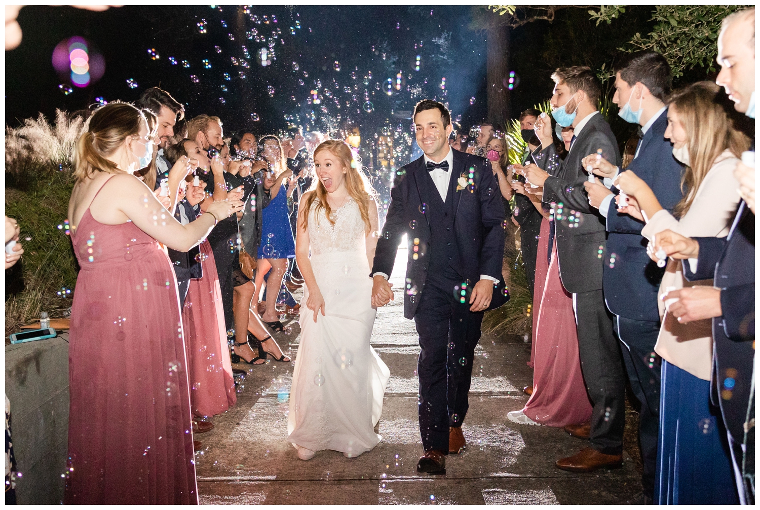 bride and groom running through bubbles exiting reception