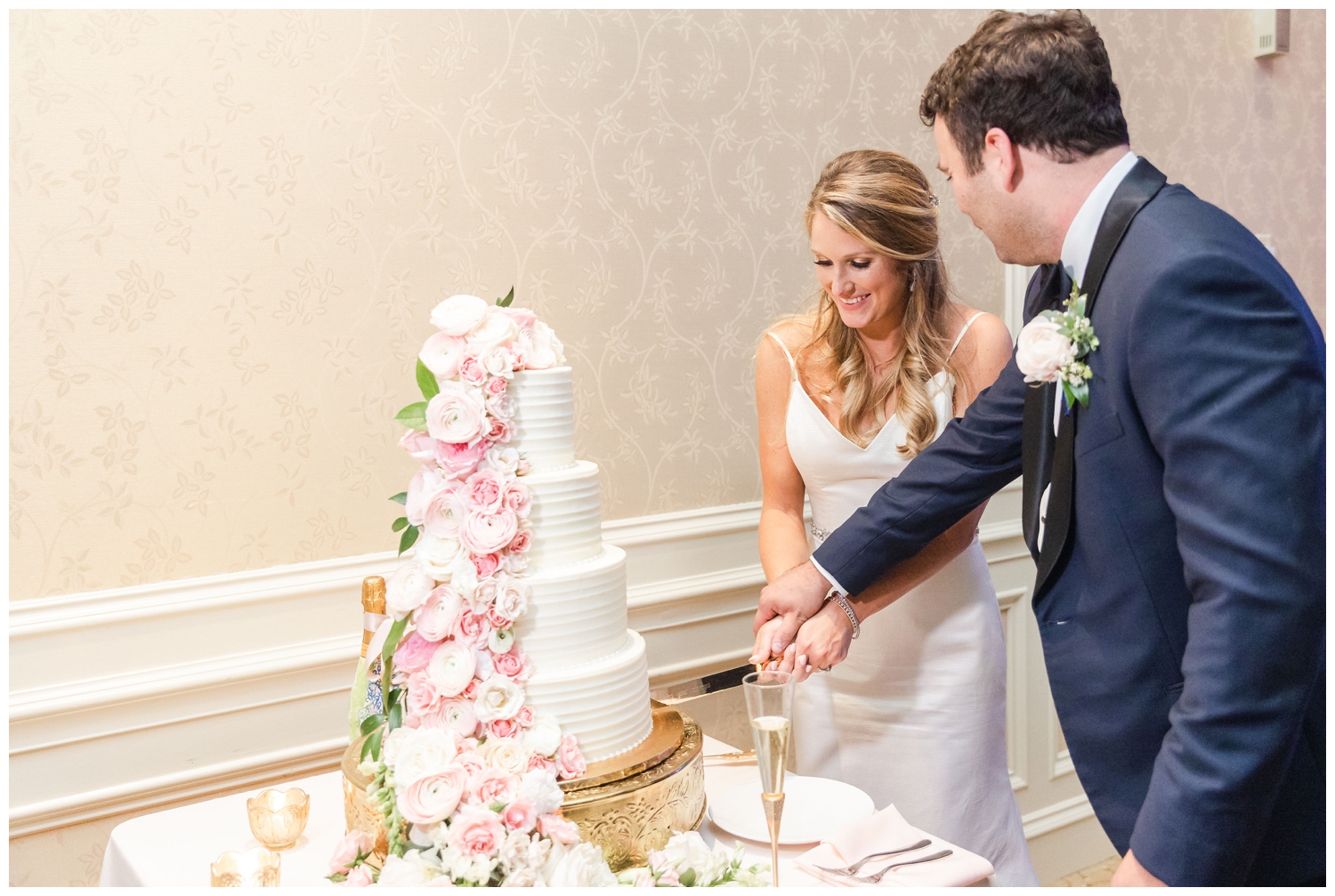 bride and groom cutting white cake with pink florals