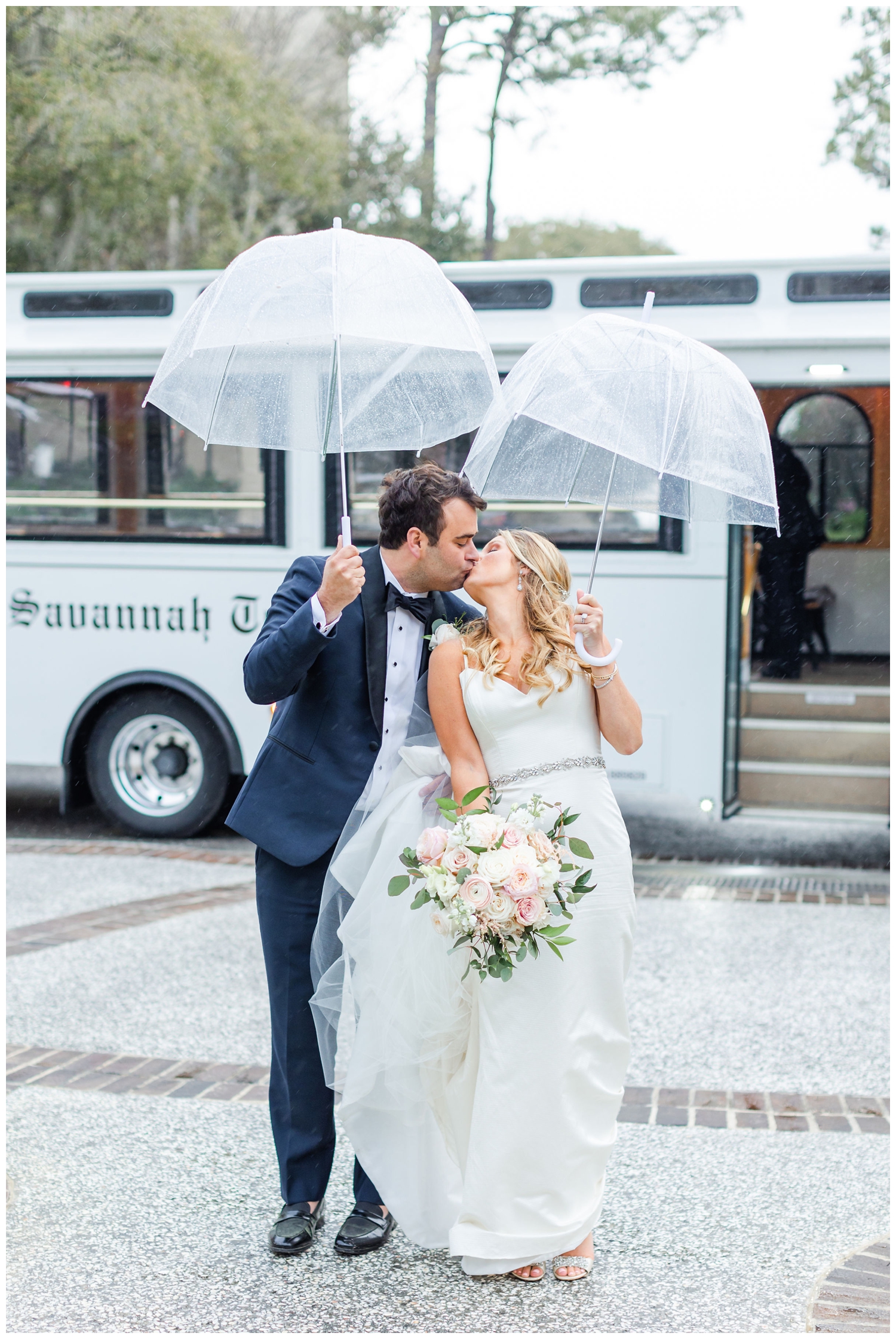 bride and groom kissing under clear umbrella