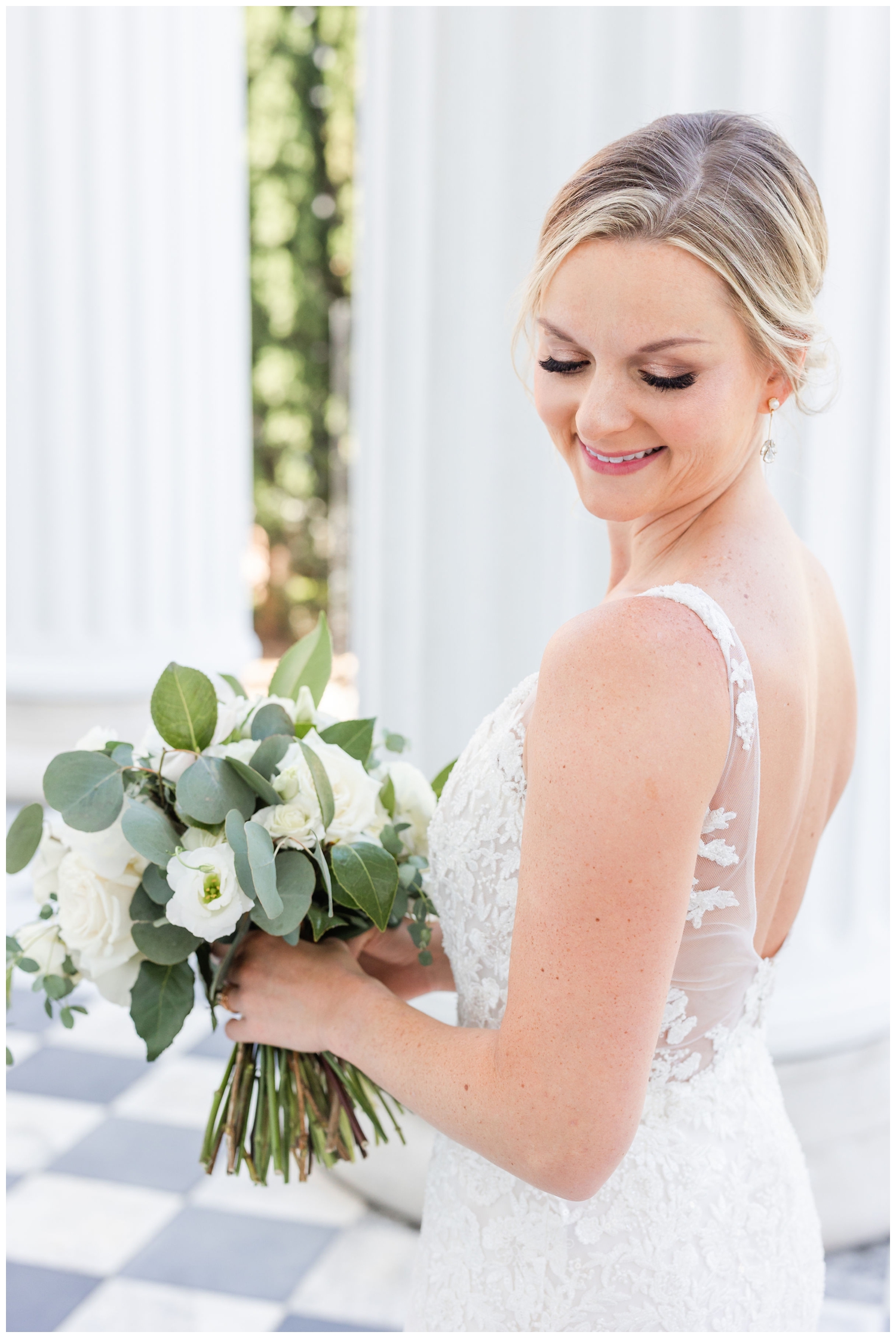 bride looking over her shoulder with white rose bouquet