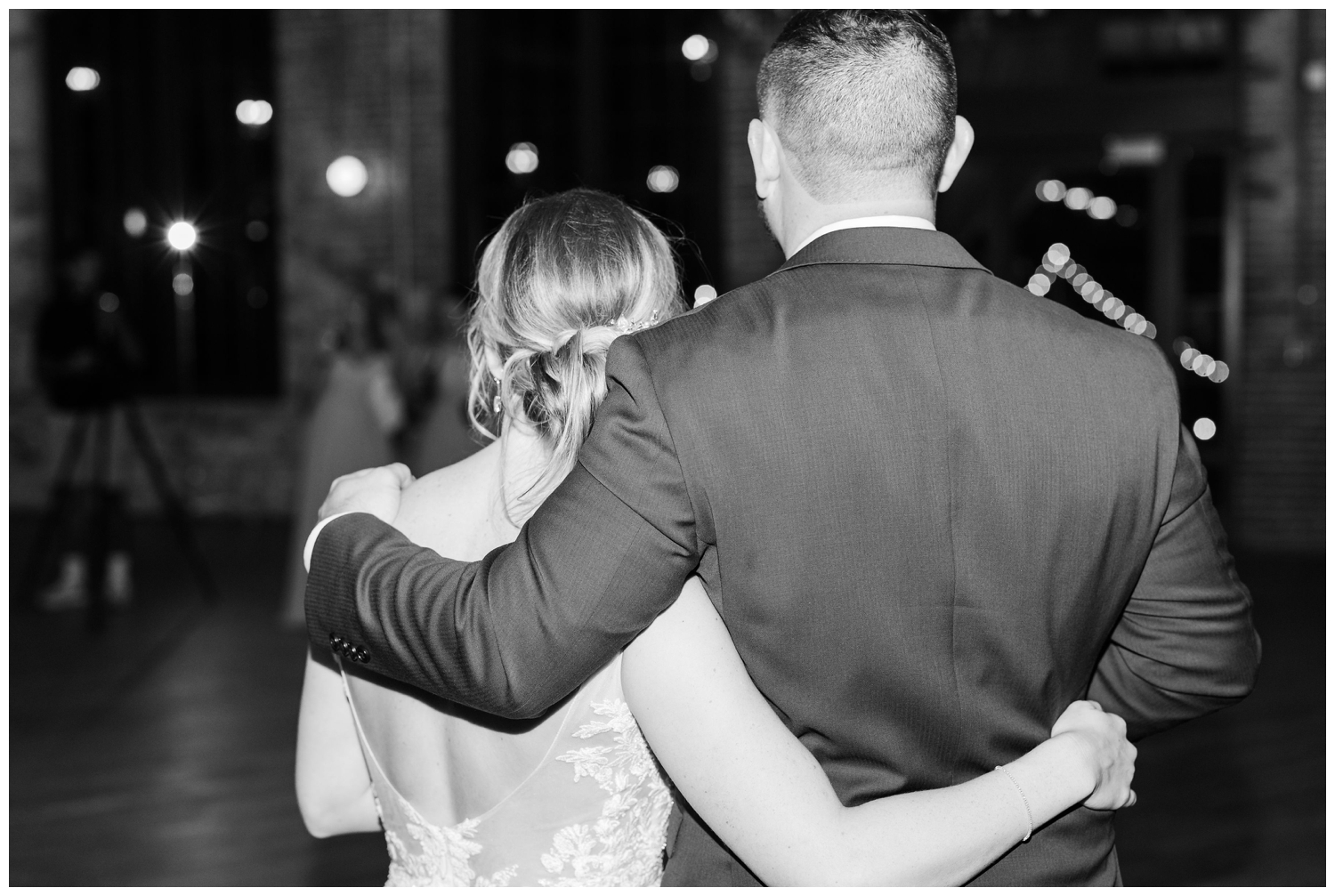 black and white photo from the back of bride and groom hugging