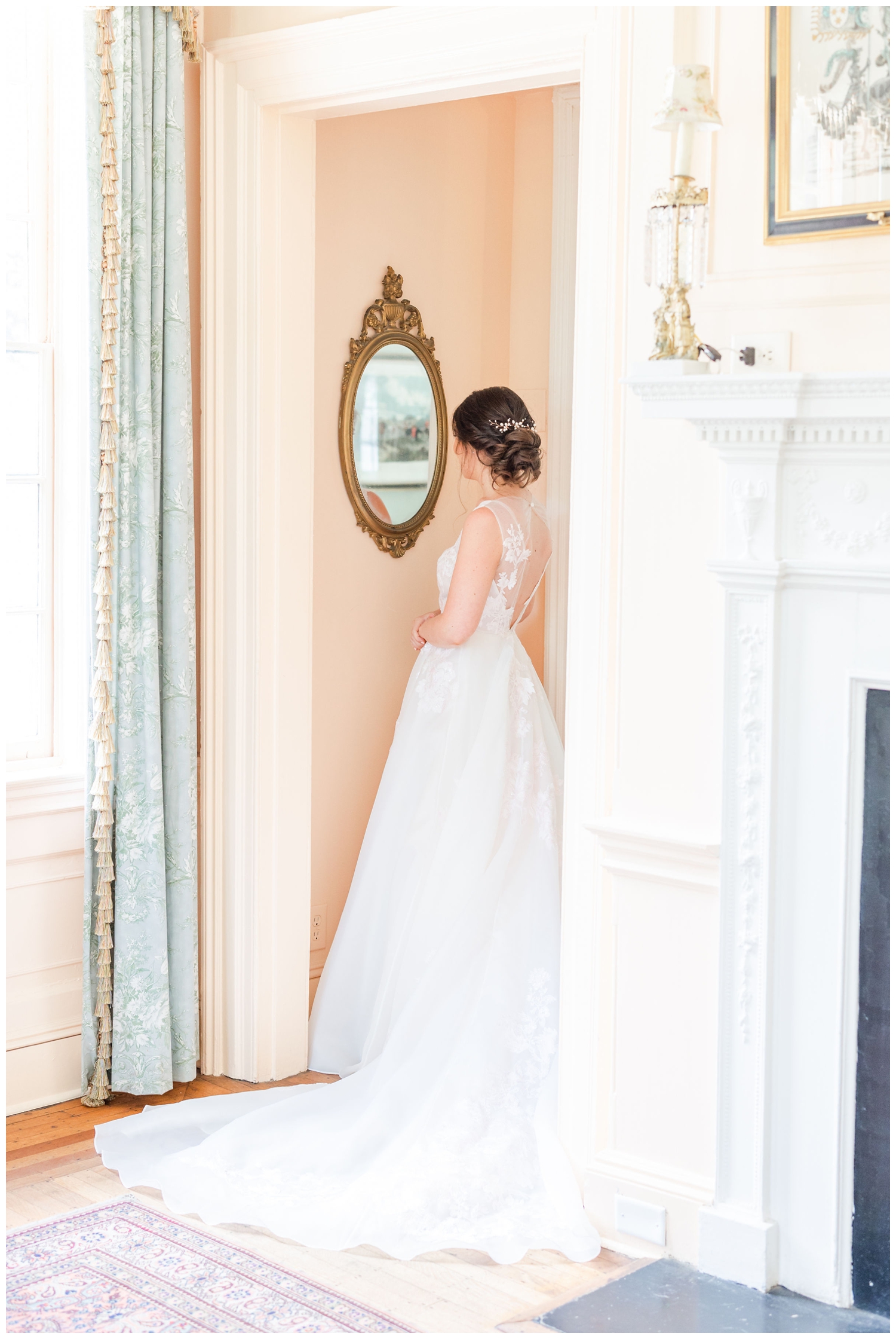 bride in wedding gown looking into a gold mirror spring Lowndes Grove wedding in Charleston South Carolina