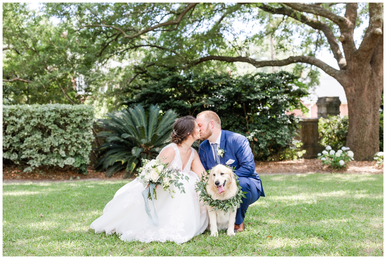 bride and groom kissing portrait with dog and flower collar under oak tree at Lowndes Grove