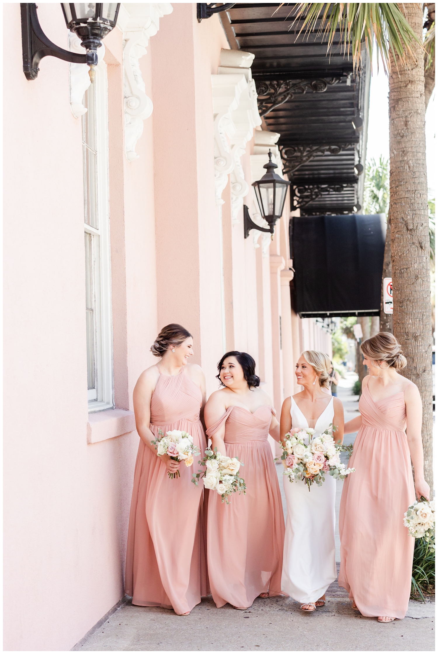 bride and bridesmaid with blush pink dresses walking outside Mills House at southern summer wedding Charleston