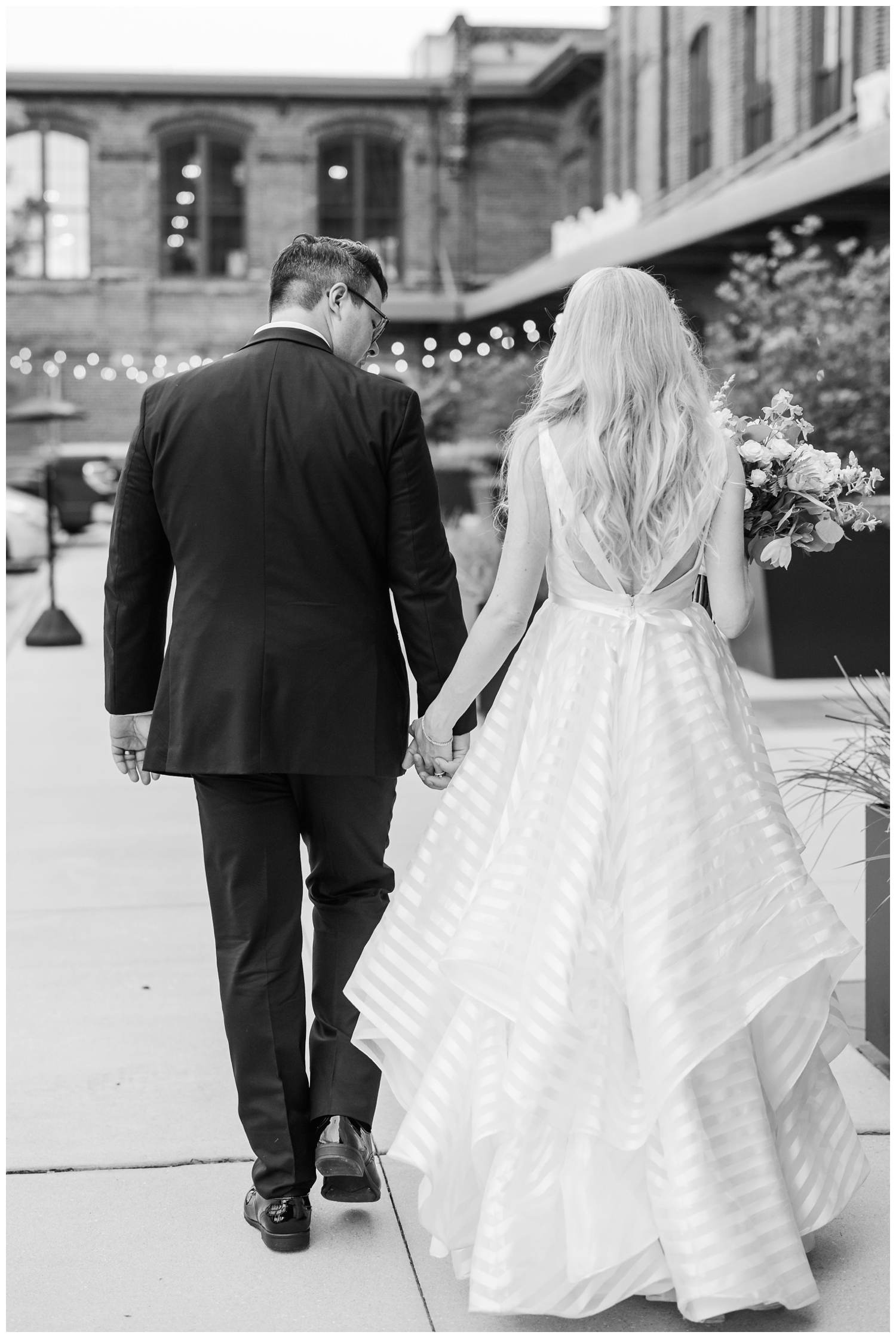 black and white photo bride and groom holding hands on Charleston street
