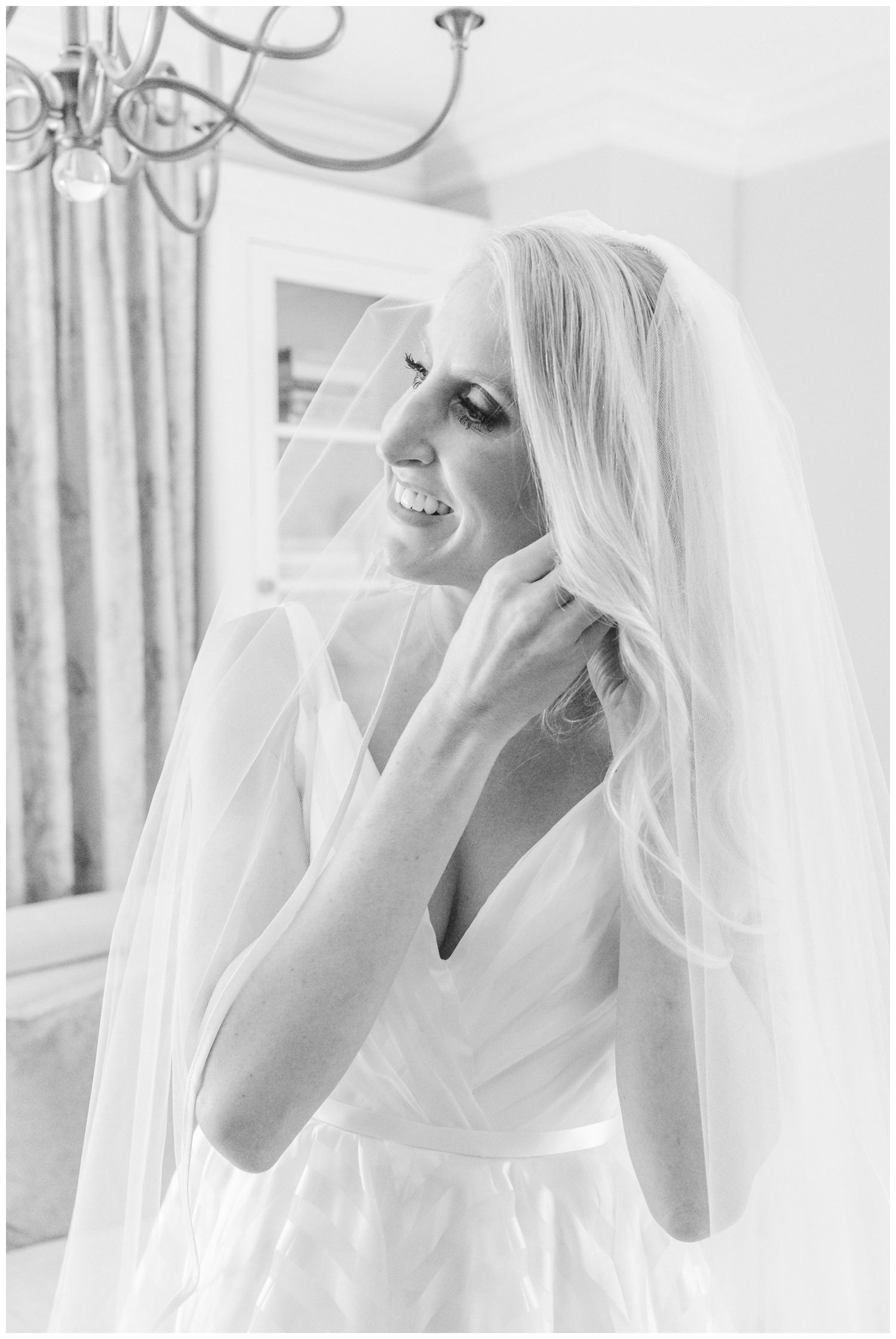 black and white photo of bride putting on earrings for Cedar Room wedding