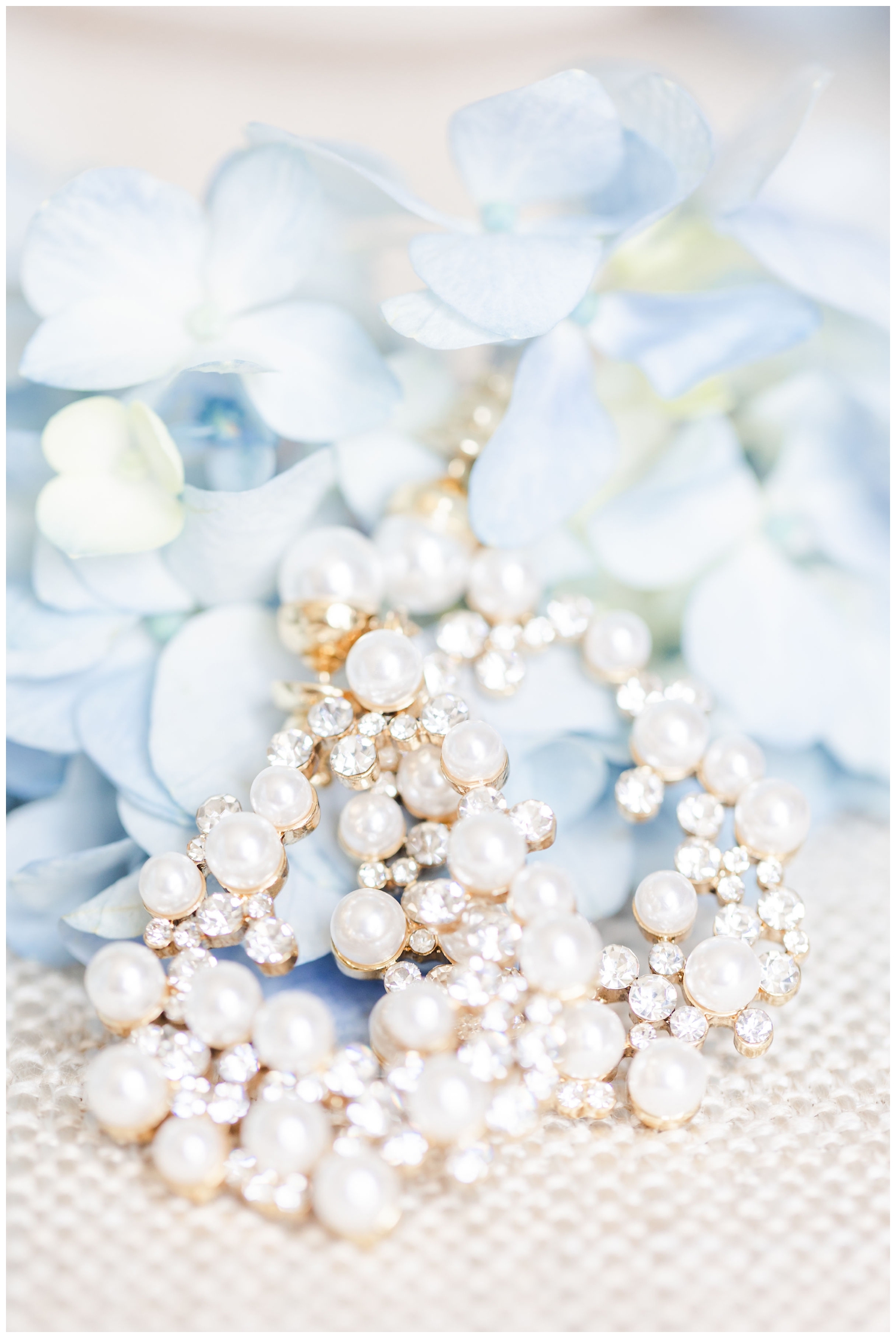 white pearl earrings surrounded by blue hydrangea floral
