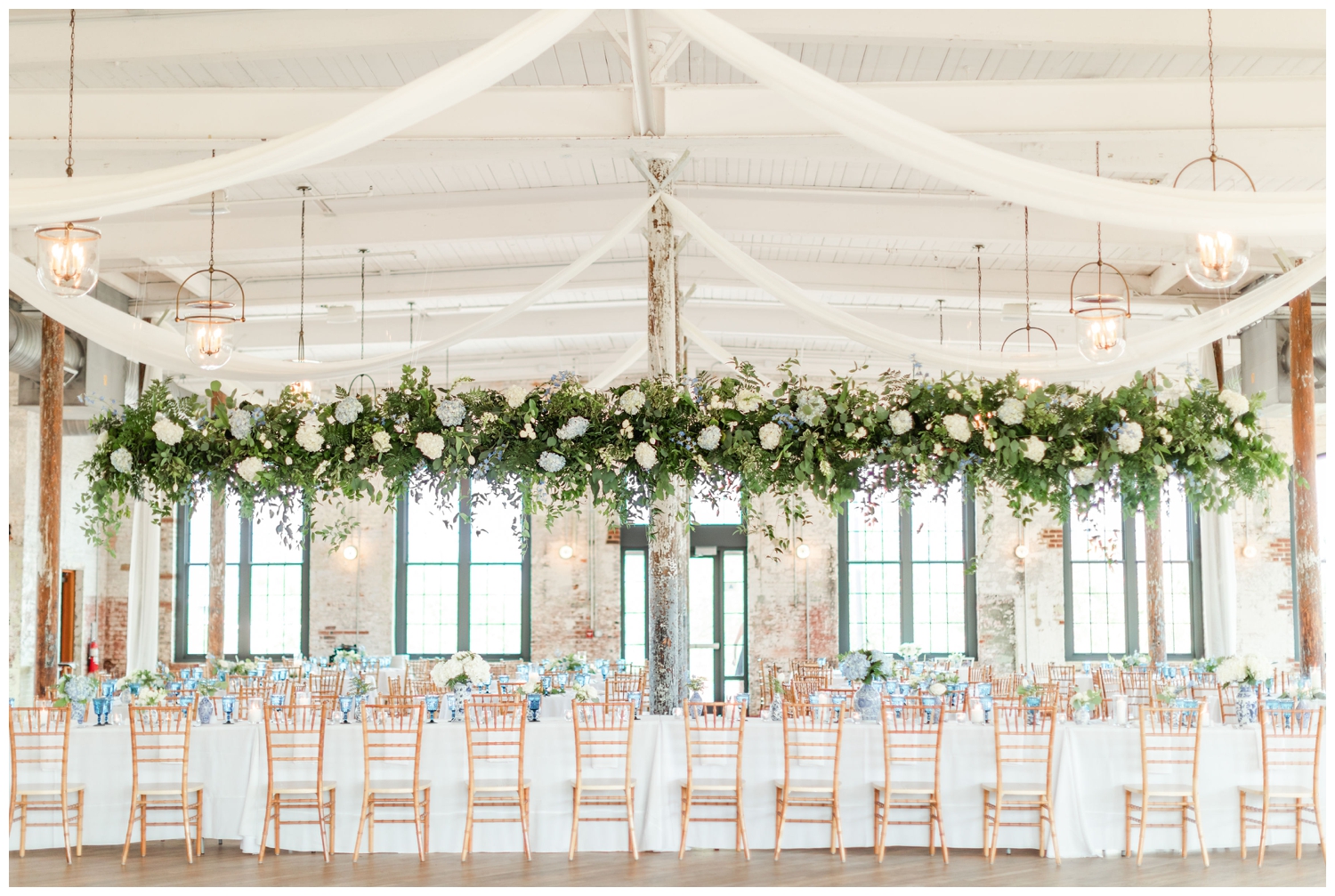 Cedar Room wedding reception with long head table and florals hanging overhead